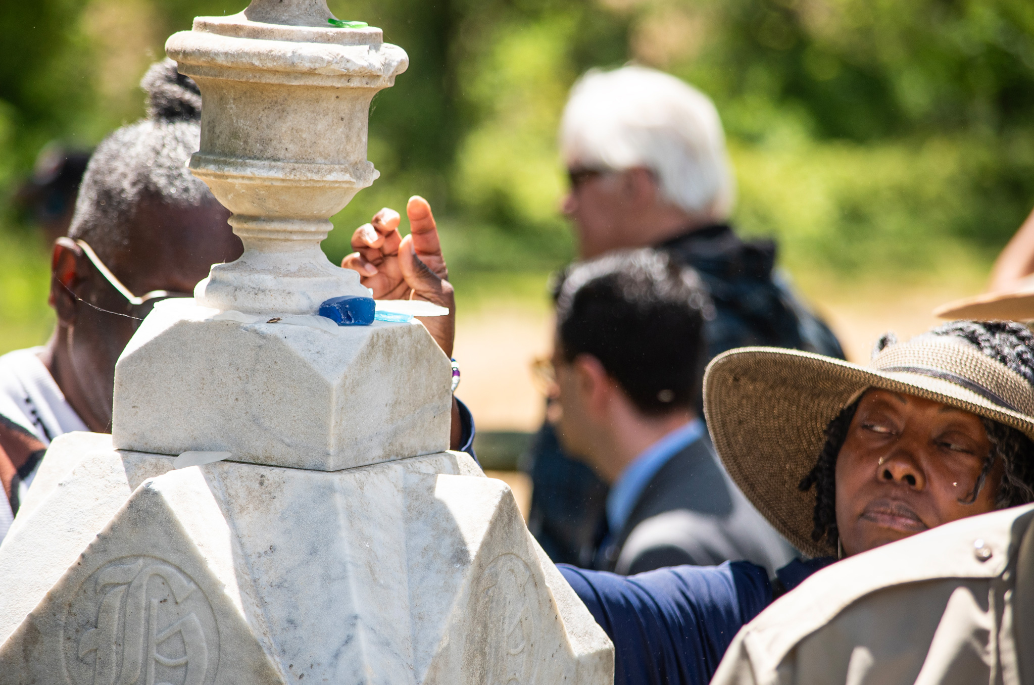 Person placing a piece of sea glass on a grave marker